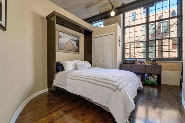 a bedroom with a bed and a large window with wooden floor