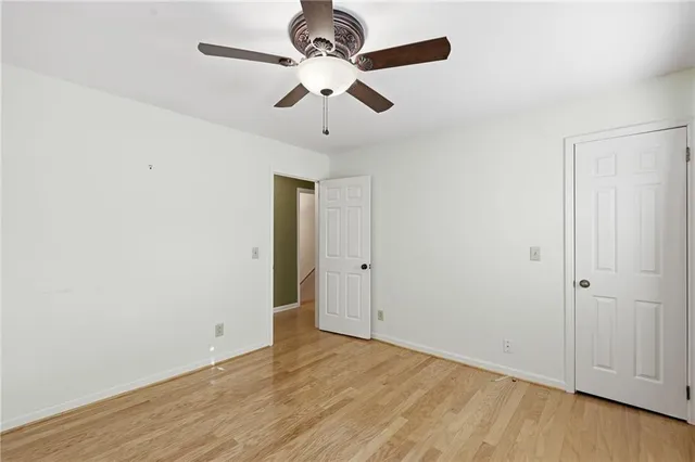an empty room with wooden floor ceiling fan and windows