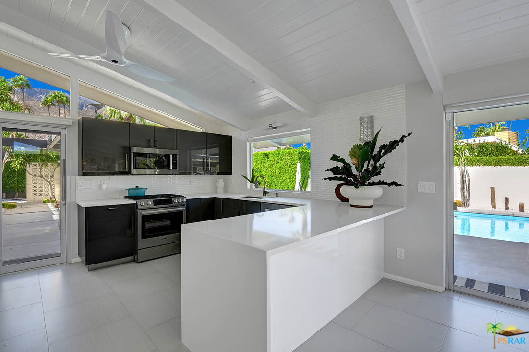 984 East La Jolla Road Palm Springs, CA 92264 - Photo 12 of 53 a large white kitchen with stainless steel appliances granite countertop a sink a stove top oven a counter space and a window