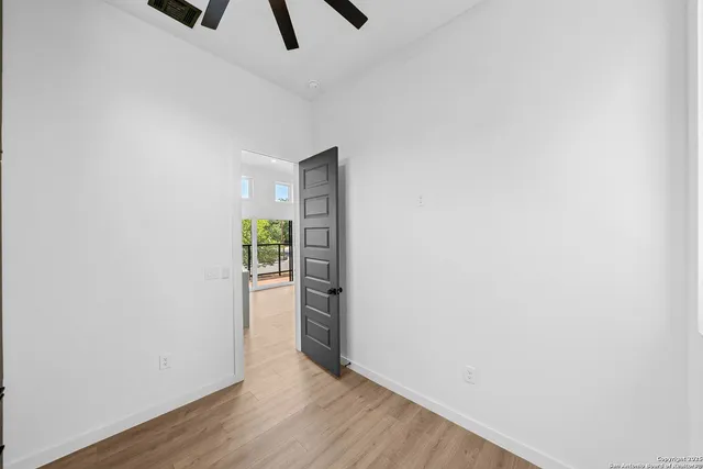 a view of kitchen and empty room with wooden floor