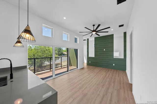 a view of a livingroom with furniture wooden floor a ceiling fan and windows