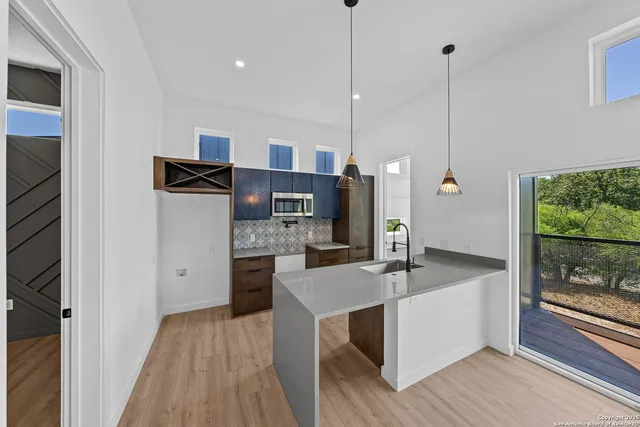 a kitchen with stainless steel appliances granite countertop a sink a refrigerator and a wooden floor