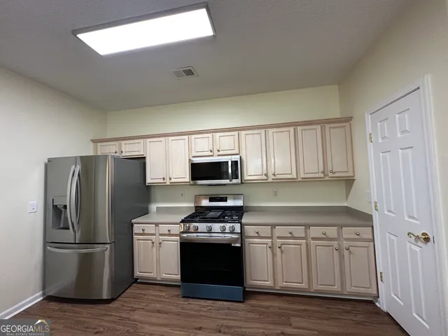 a kitchen with stainless steel appliances granite countertop a refrigerator a stove top oven a sink and dishwasher