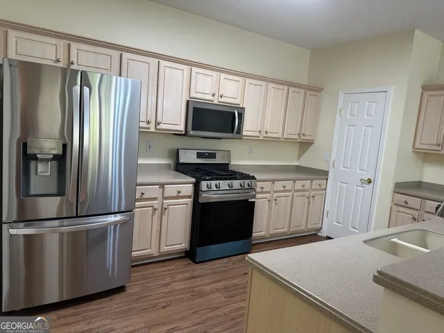 a view of an empty room with wooden floor fireplace and a window