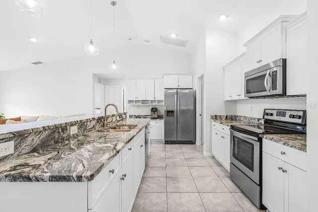 a large kitchen with stainless steel appliances granite countertop a stove top oven a refrigerator a sink and a microwave