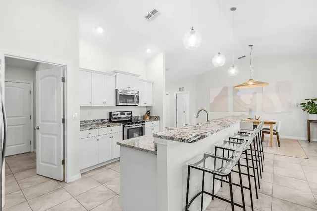 a kitchen with stainless steel appliances kitchen island granite countertop a sink a stove a refrigerator and cabinets