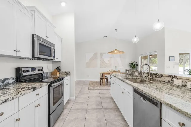 a large kitchen with stainless steel appliances granite countertop a sink and cabinets