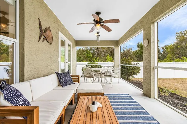 a living room with a rug floor to ceiling windows and a table