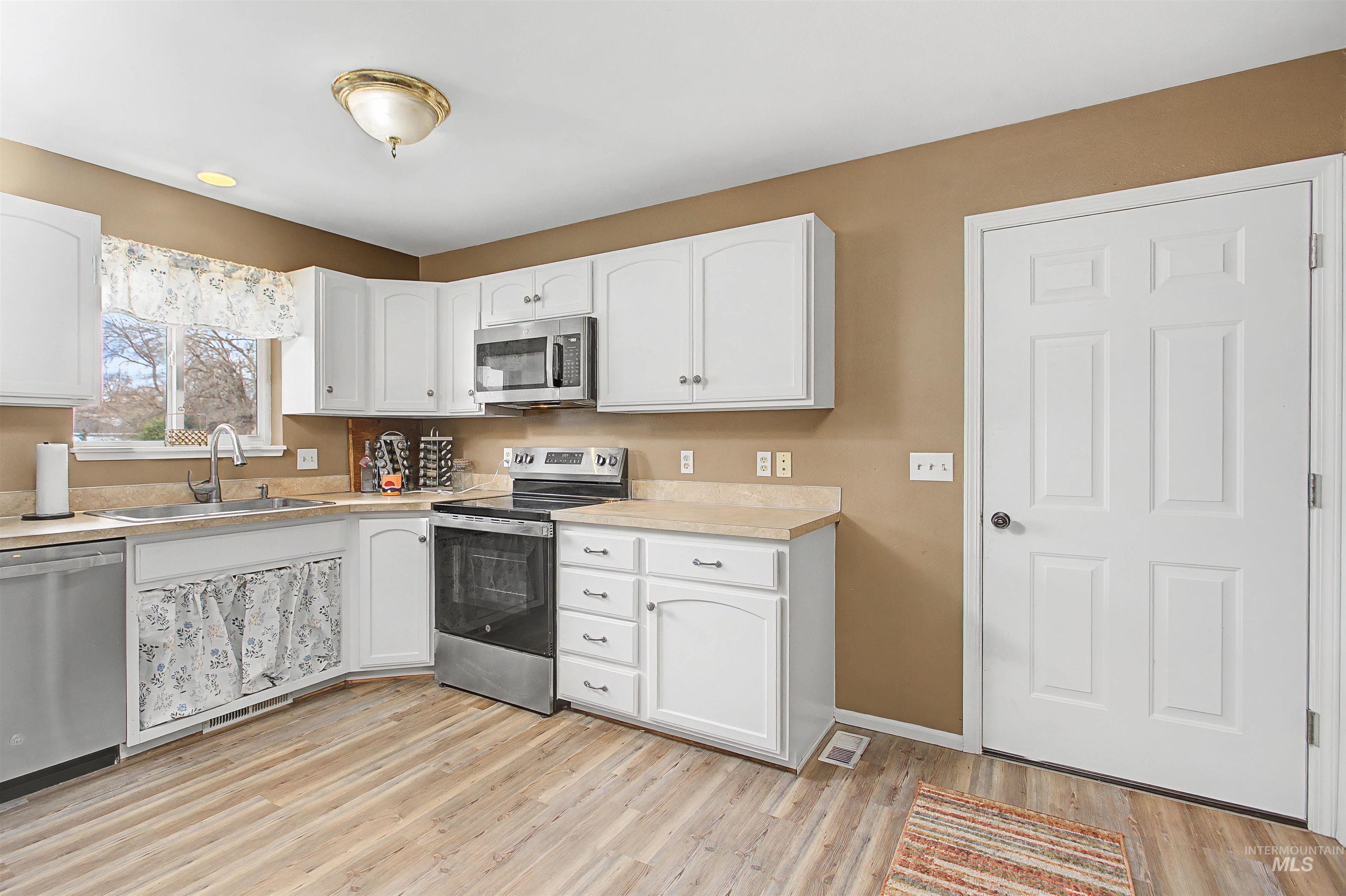 919 9th Street Clarkston, WA 99403 - Photo 13 of 34 Kitchen featuring stainless steel appliances, light countertops, white cabinetry, and light wood-type flooring