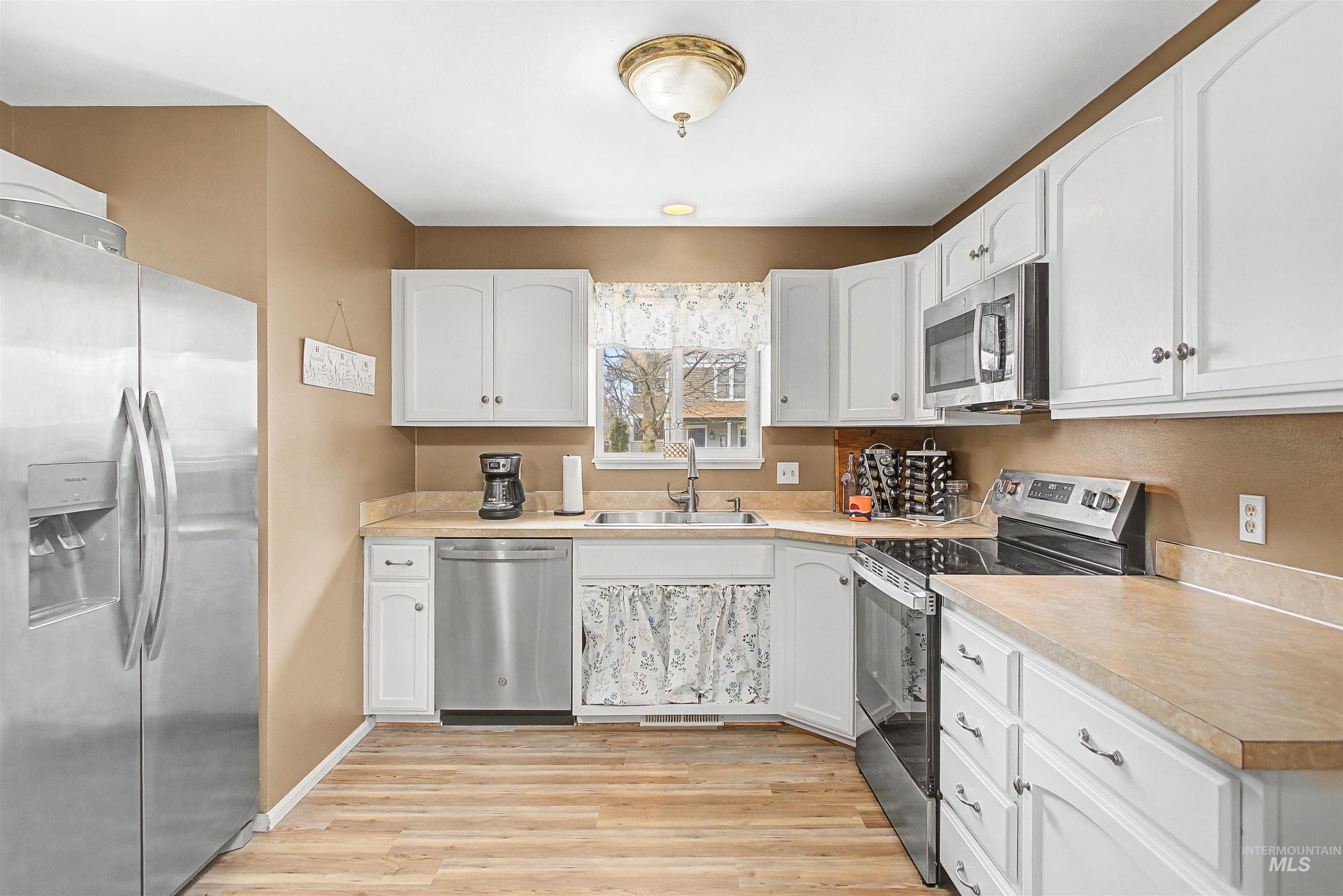919 9th Street Clarkston, WA 99403 - Photo 14 of 34 Kitchen featuring stainless steel appliances, light countertops, white cabinets, and light wood-style floors