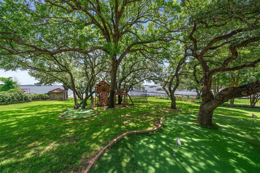 9930 Boat Club Road Fort Worth, TX 76179 - Photo 38 of 40 Enjoy a beautifully landscaped backyard at the primary residence with putting greens, mature oak trees, and scenic views of the lake.