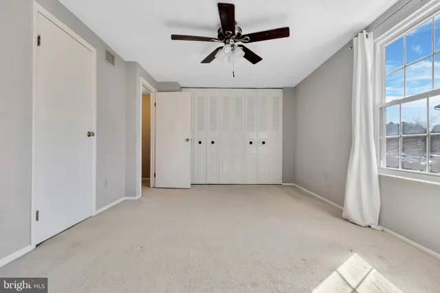 an empty room with windows and fan