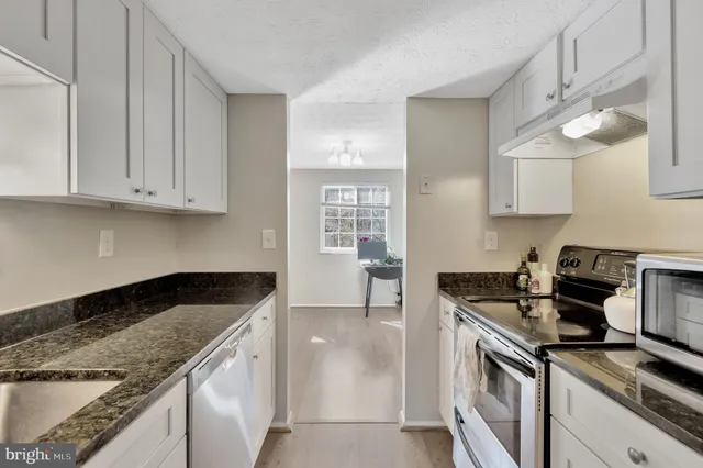 a kitchen with granite countertop a sink a stove and cabinets