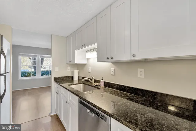 a kitchen with granite countertop a sink a stove and cabinets
