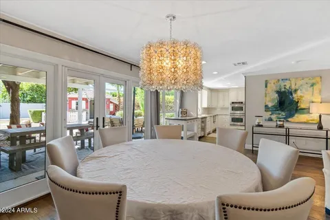 a kitchen with stainless steel appliances kitchen island granite countertop a stove a sink a dining table and chairs with wooden floor