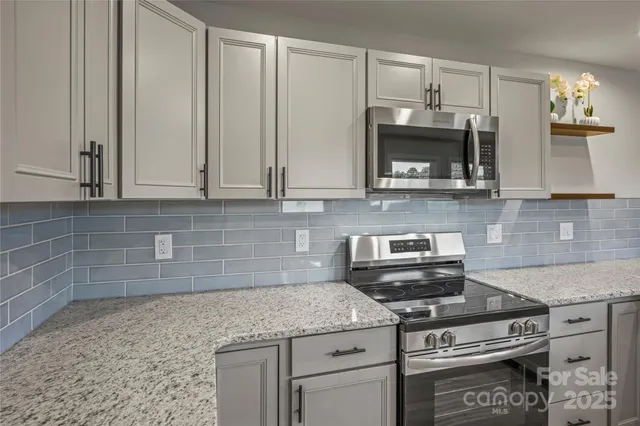 a kitchen with stainless steel appliances kitchen island granite countertop a refrigerator a stove and a sink