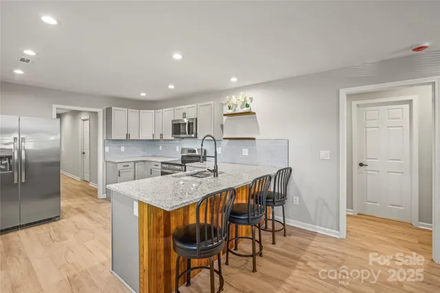 a kitchen with stainless steel appliances granite countertop a dining table chairs refrigerator and sink