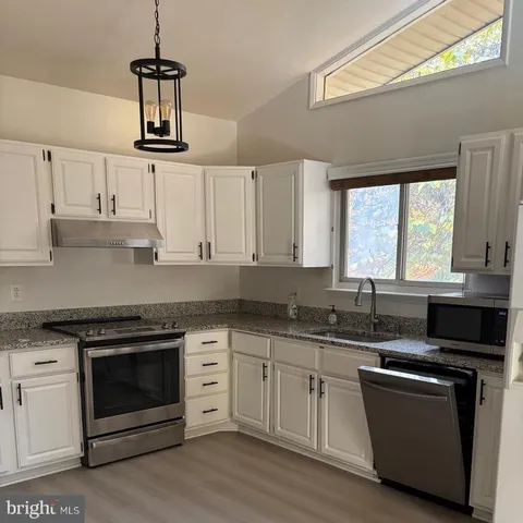 a kitchen with cabinets stainless steel appliances a sink and a window