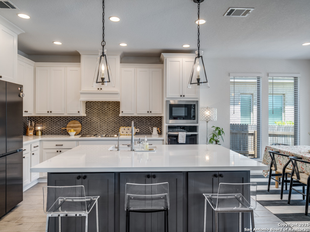 25902 Madison Ranch San Antonio, TX 78255 - Photo 16 of 36 a kitchen with cabinets a sink stove and refrigerator with wooden floor