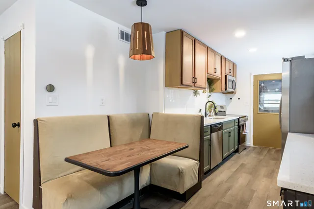 a living room with stainless steel appliances kitchen island granite countertop furniture and a wooden floor