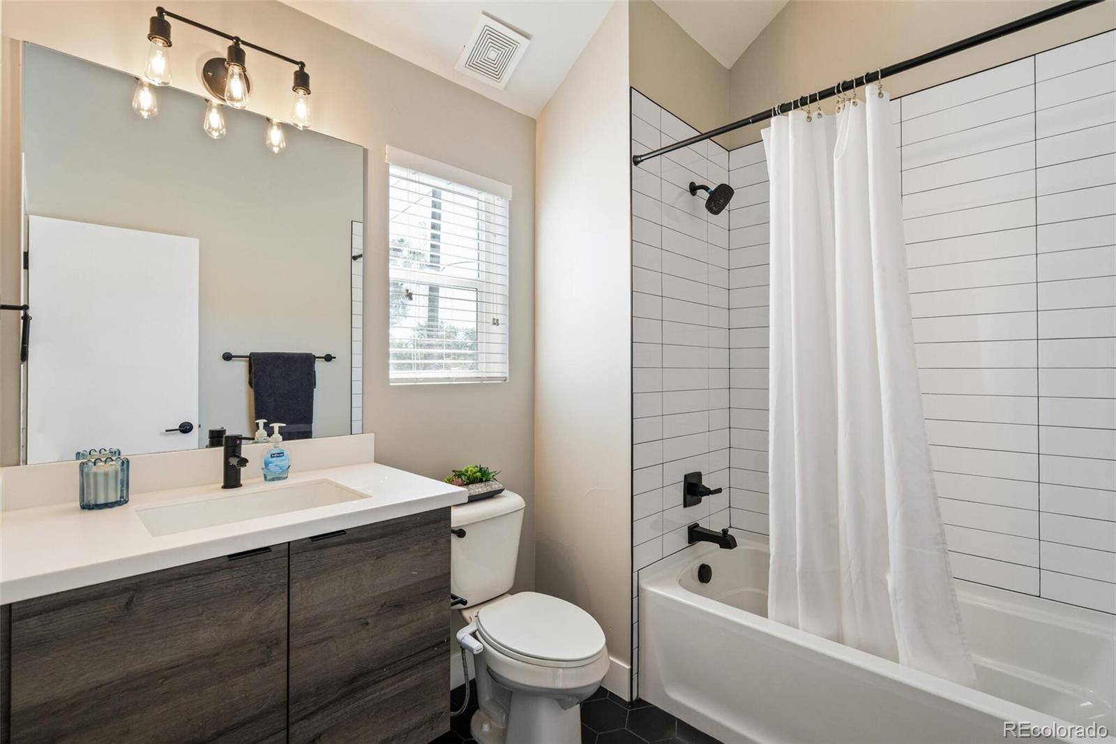 4306 Sherman Street Denver, CO 80216 - Photo 21 of 32 a bathroom with a sink a toilet a mirror a vanity and shower