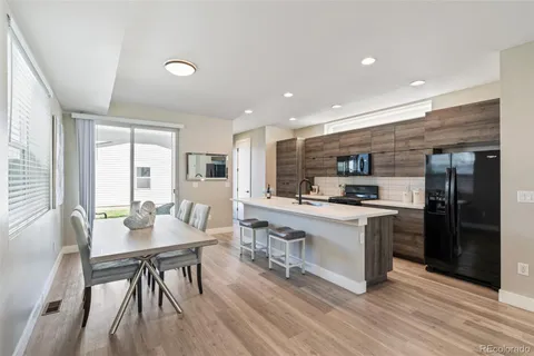 a kitchen with stainless steel appliances granite countertop a stove top oven a sink dishwasher a dining table and chairs with wooden floor