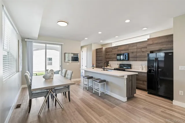 a kitchen with stainless steel appliances granite countertop a stove top oven a sink dishwasher a dining table and chairs with wooden floor