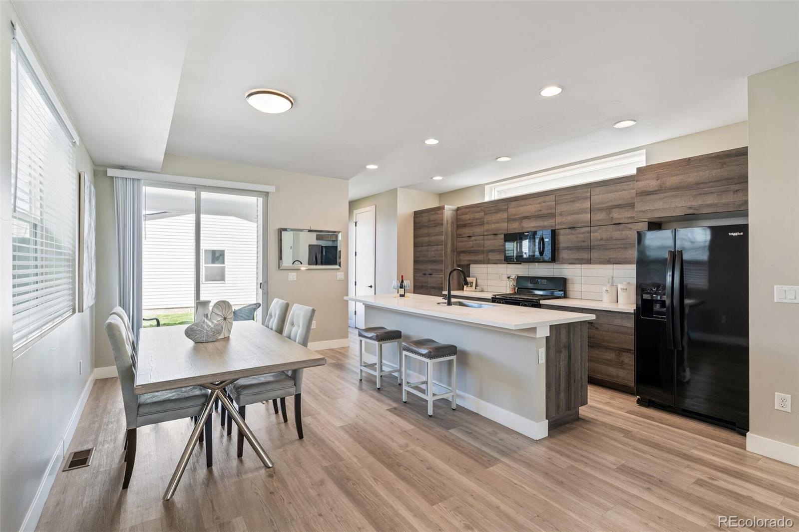4306 Sherman Street Denver, CO 80216 - Photo 6 of 32 a kitchen with stainless steel appliances granite countertop a stove top oven a sink dishwasher a dining table and chairs with wooden floor