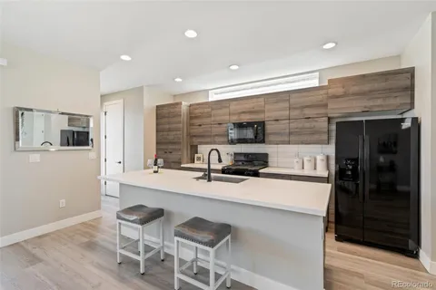 a kitchen with stainless steel appliances a sink a stove a refrigerator cabinets and a dining table