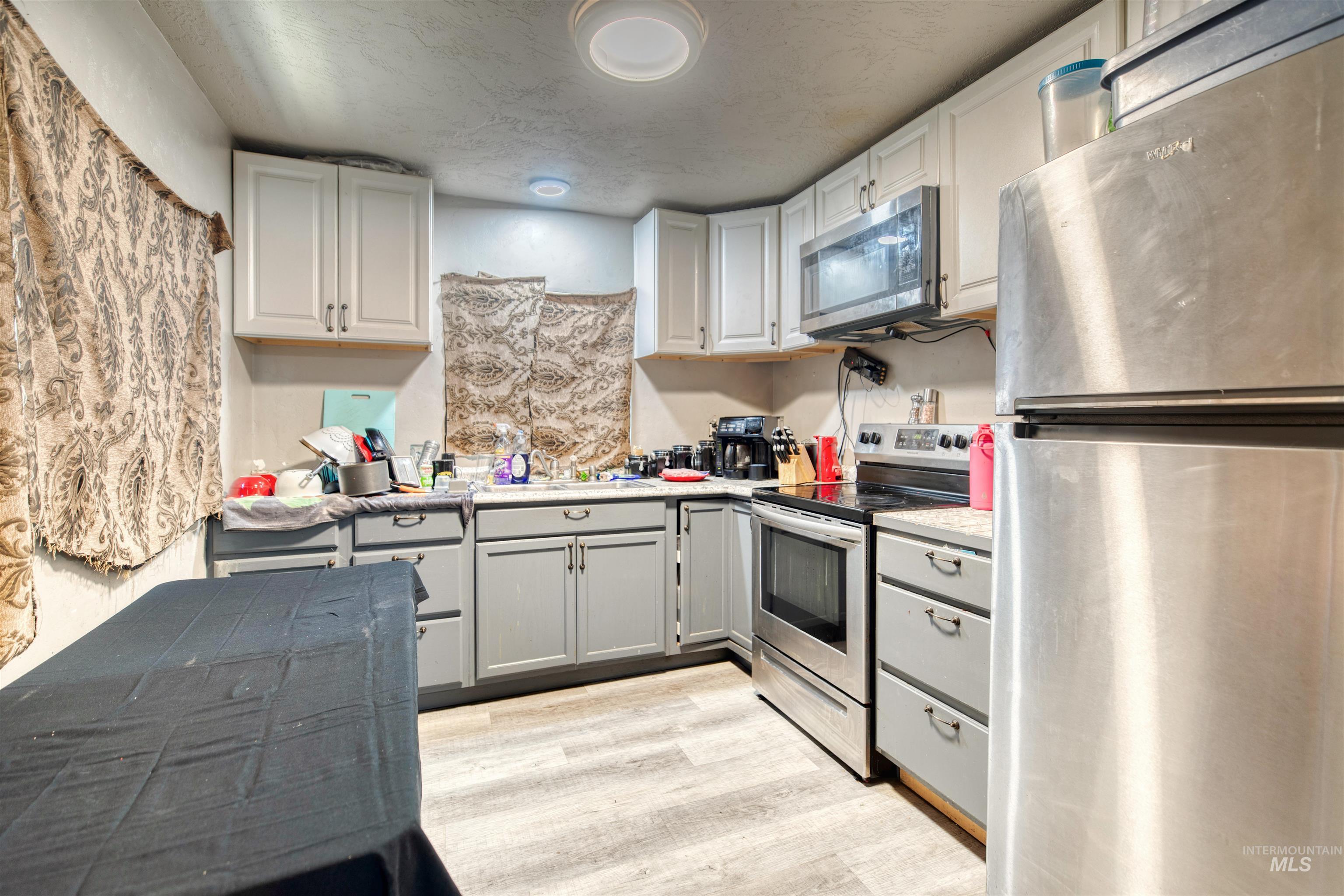 106 East Main Street Nyssa, OR 97913 - Photo 28 of 32 Kitchen featuring appliances with stainless steel finishes, light countertops, light wood-style flooring, and white cabinets