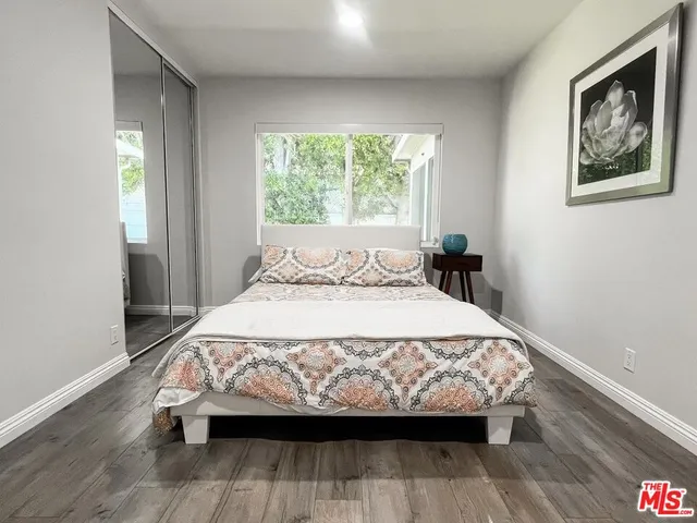 a bedroom with a bed a window and wooden floor
