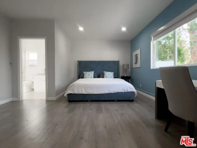 a bedroom with a bed chair and wooden floor