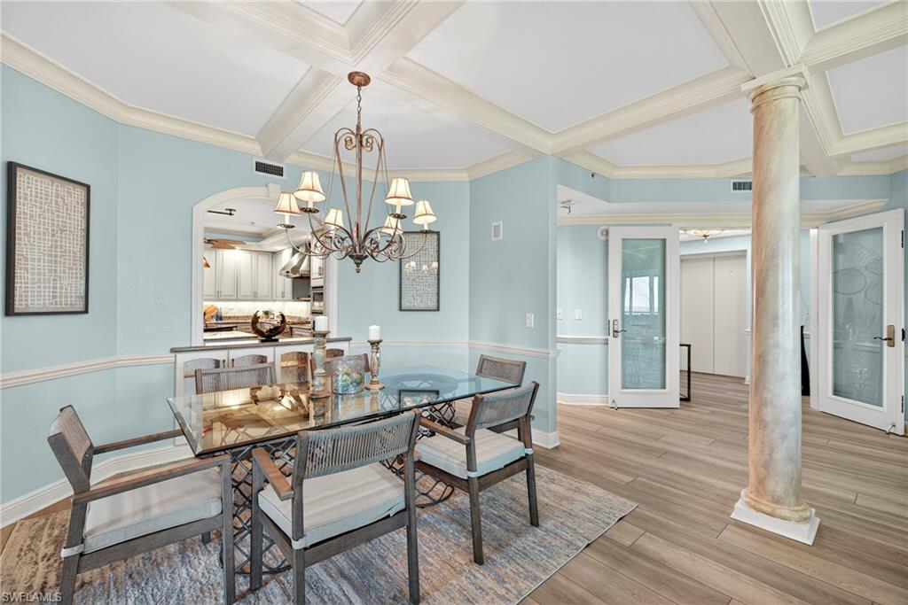 285 Grande Way, Unit 804 Naples, FL 34110 - Photo 9 of 50 a dining room with wooden floor a chandelier a wooden table and chairs