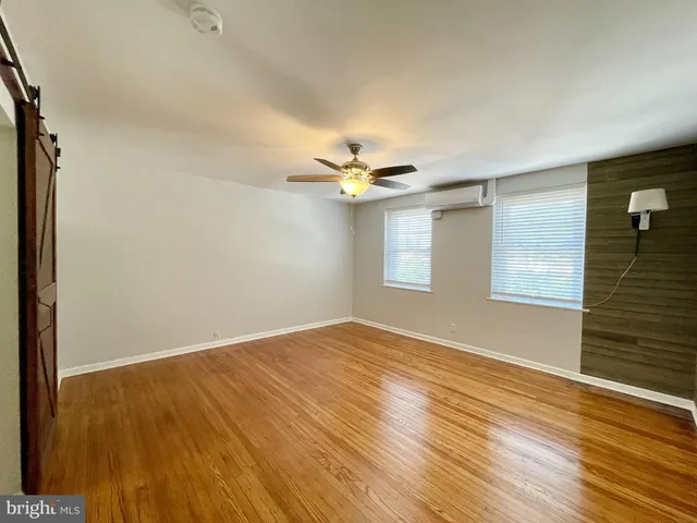 a view of empty room with wooden floor and fan