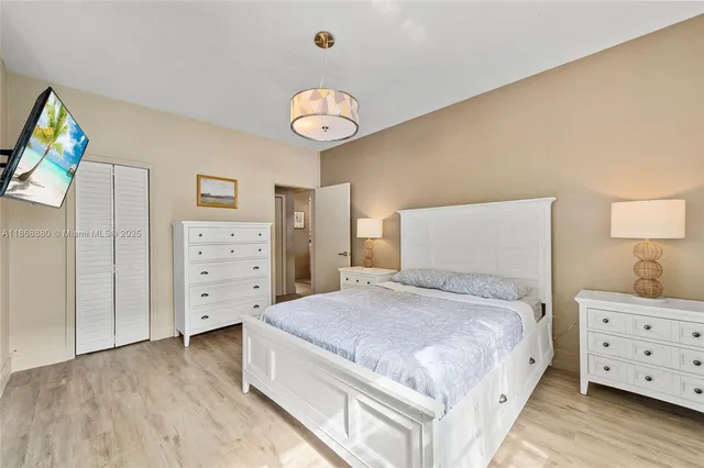 a spacious bedroom with a bed and a tv on dresser