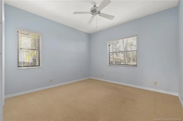 an empty room with a window and ceiling fan