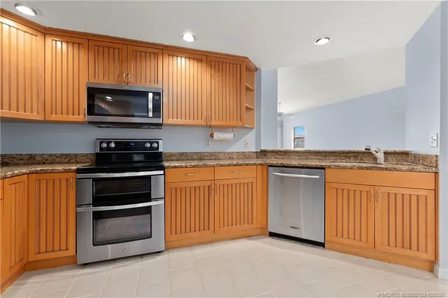 a kitchen with stainless steel appliances granite countertop a stove a sink and a microwave