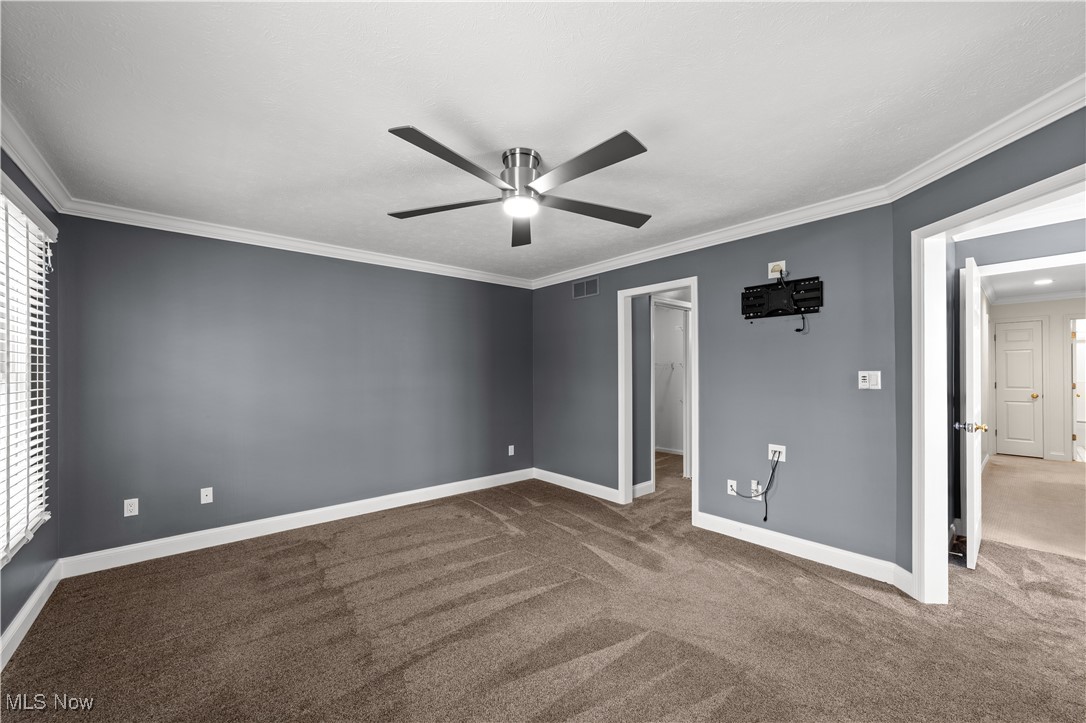 4500 Brooks Road Cleveland, OH 44105 - Photo 21 of 50 Primary bedroom with crown molding, a spacious closet, carpet flooring, and ceiling fan
