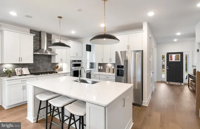 a kitchen with stainless steel appliances a dining table chairs refrigerator and cabinets