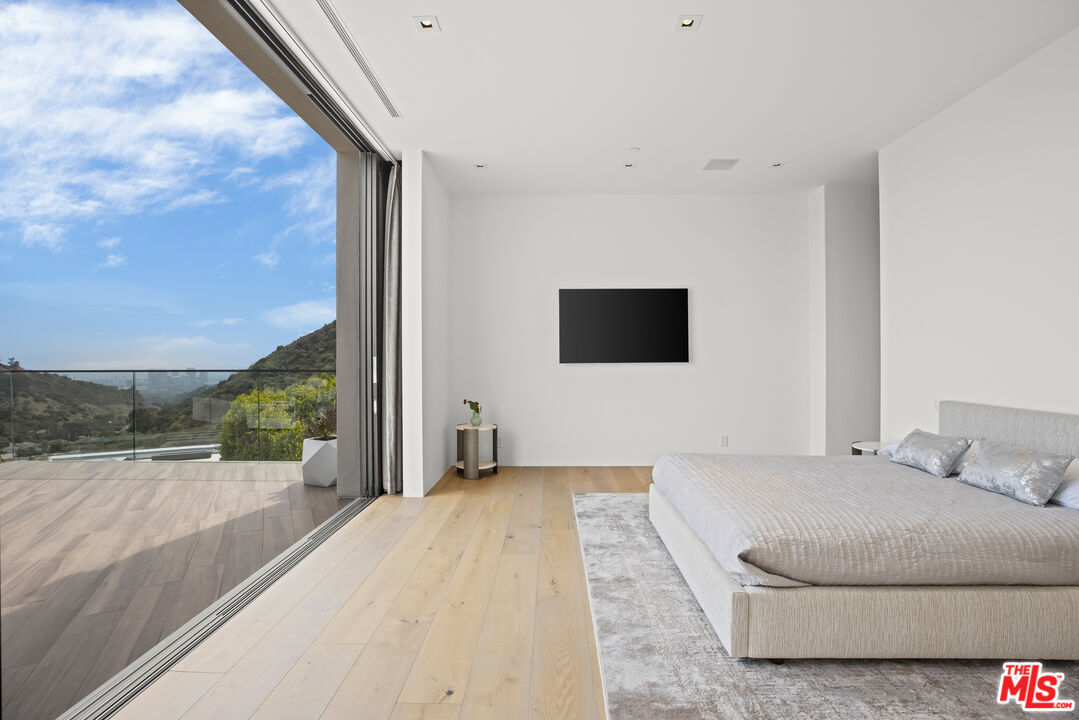 9674 Highridge Drive Beverly Hills, CA 90210 - Photo 18 of 29 a spacious bedroom with a bed and a flat screen tv