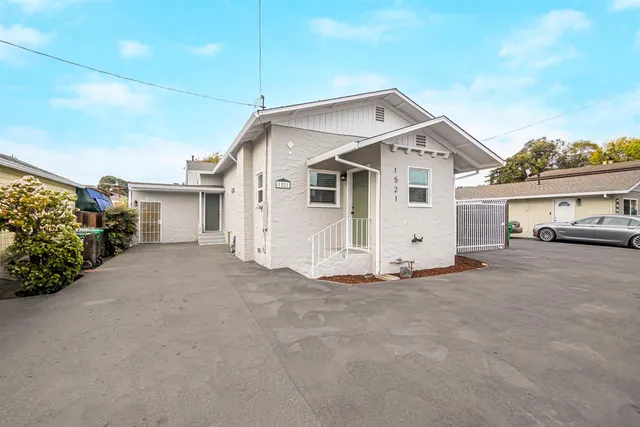 a view of a white house with a small yard and parking space