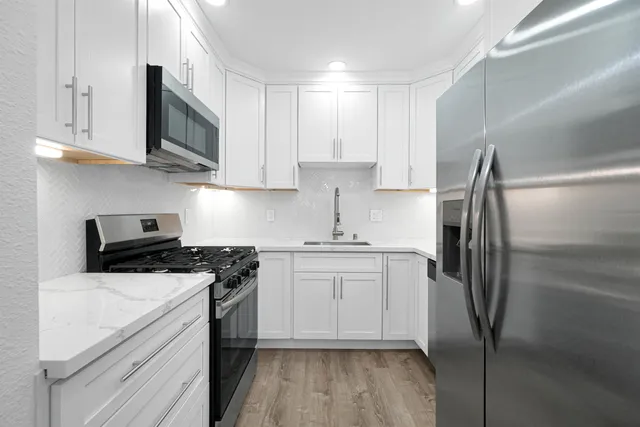 a kitchen with a sink stainless steel appliances and white cabinets
