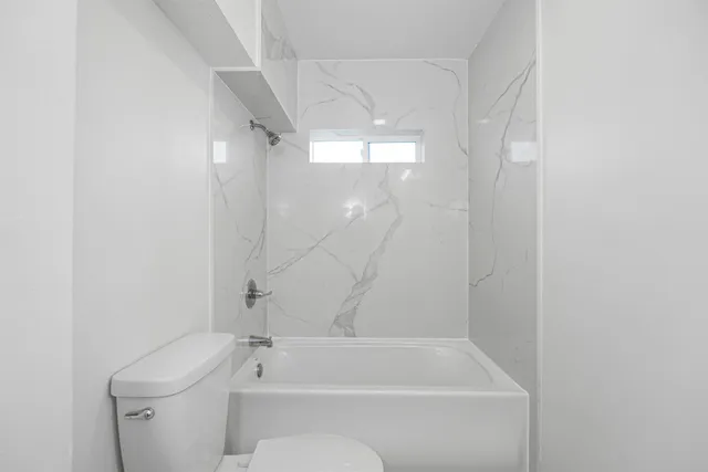 a bathroom with a shower a toilet and a window