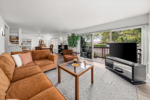 a living room with furniture a flat screen tv and a floor to ceiling window