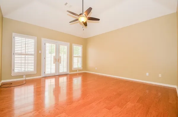 a view of an empty room with a window and wooden floor