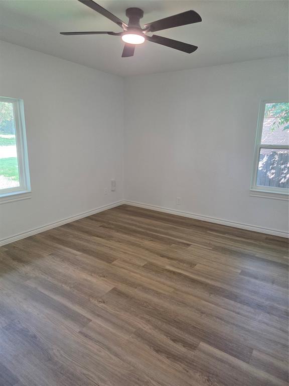 2108 Blake Avenue Dallas, TX 75228 - Photo 9 of 13 Spacious bedroom featuring wood-finish flooring, white baseboards, and a ceiling fan with integrated lighting