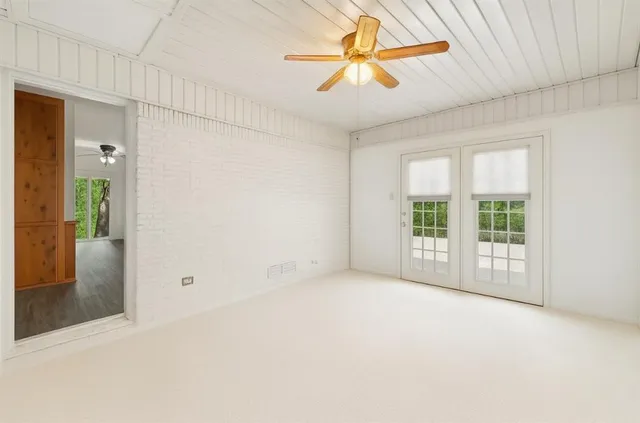 an empty room with chandelier fan and windows
