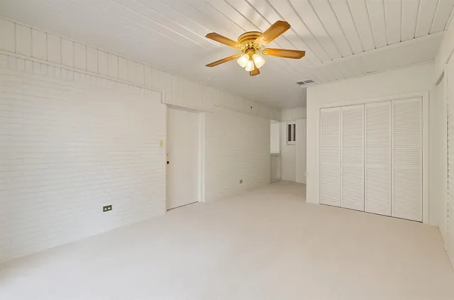 an empty room with a chandelier fan and windows