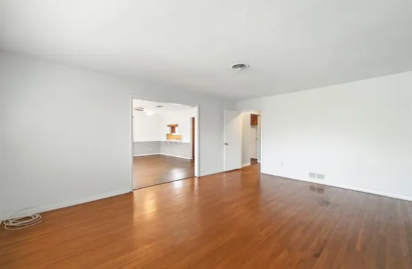 an empty room with wooden floor and natural light