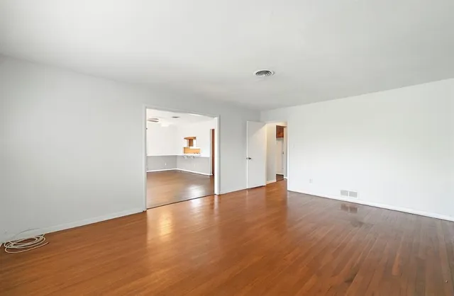 an empty room with wooden floor and natural light